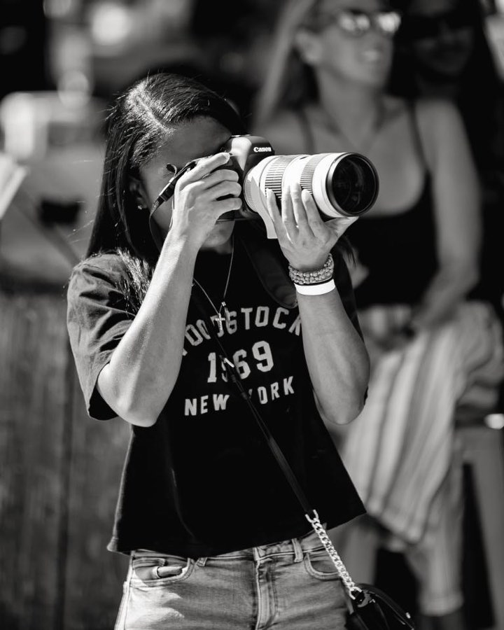 Danielle Domond photographing with a Canon camera and telephoto lens, in black and white
