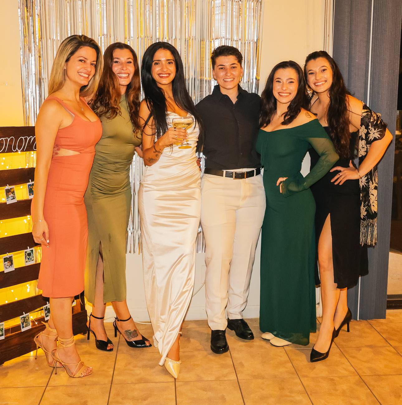 Six friends dressed up and beaming together at the engagement party