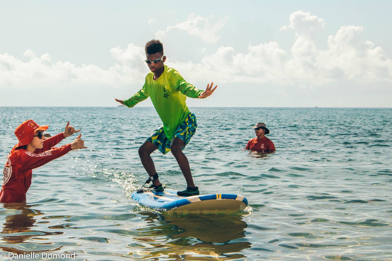 A young surfer riding a green board with arms out