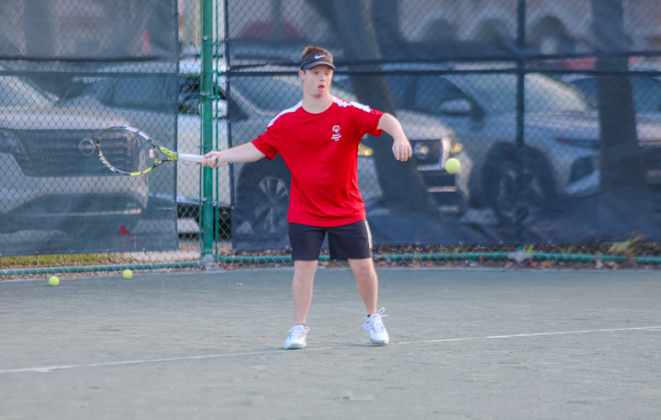A Special Olympics athlete in red lining up a forehand on the practice court