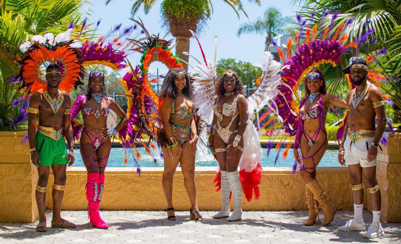Five carnival masqueraders in full costume by a fountain