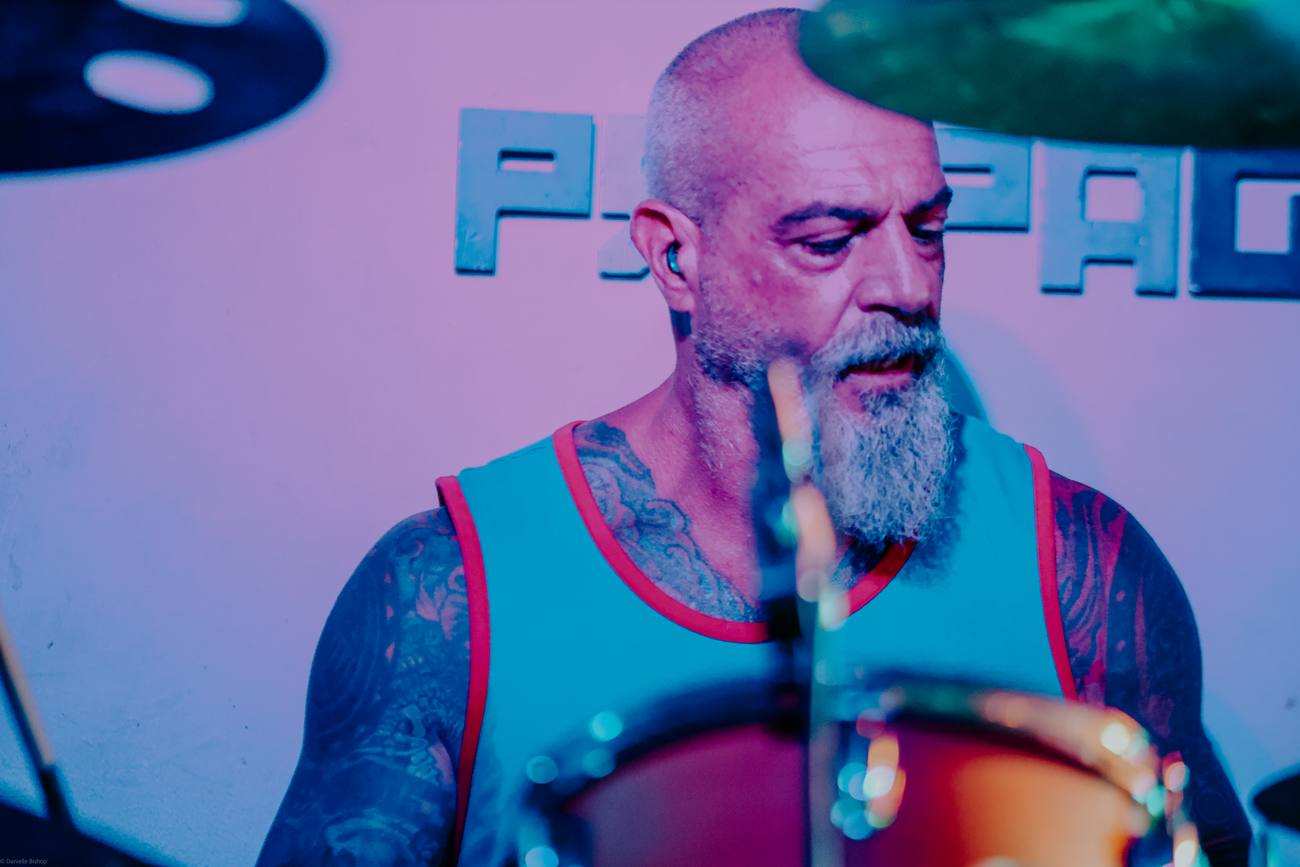 Goat Rope's drummer behind the kit, washed in pink and blue stage light