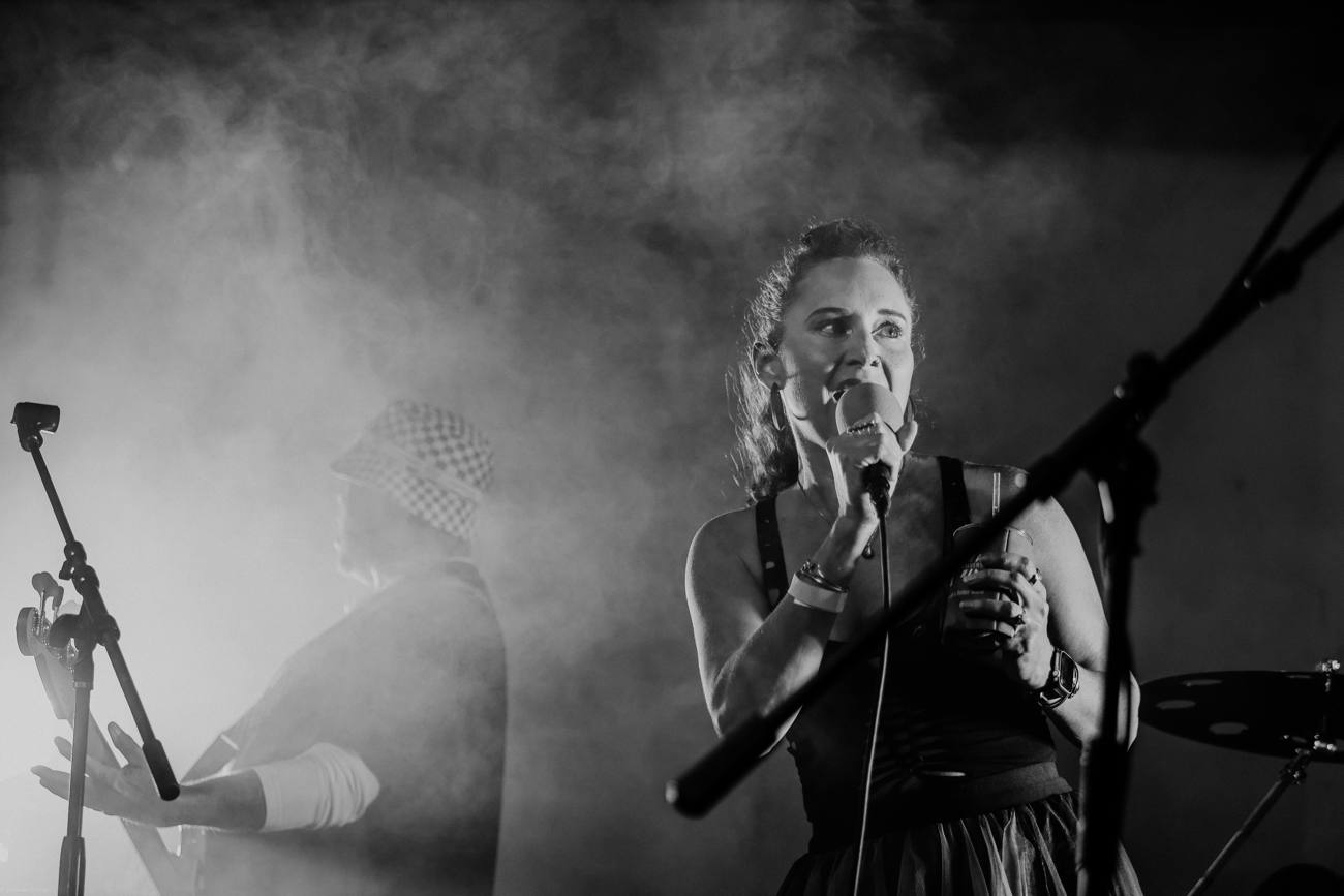 A singer in the smoke, microphone raised, in black and white