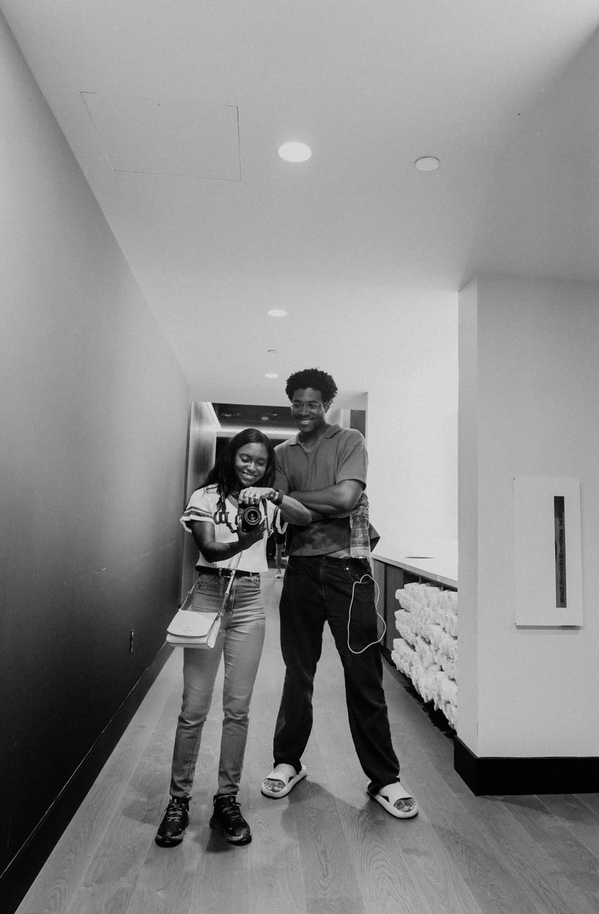 A black and white mirror photograph of the photographer and her companion checking a frame