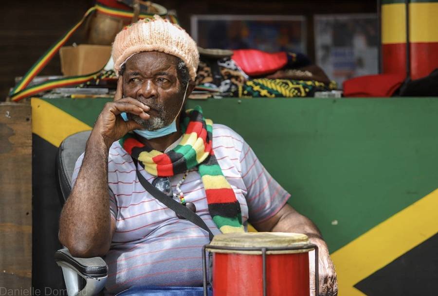 Drummer in a rasta hat with a Jamaican flag scarf mid-performance