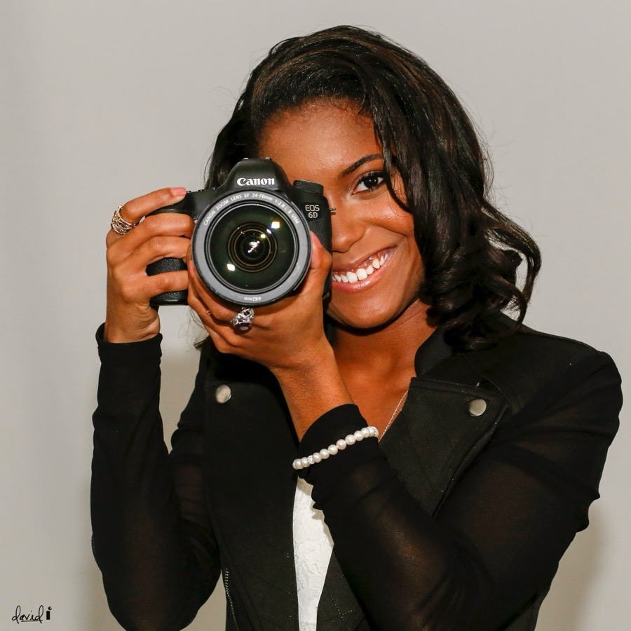 Danielle smiling behind her Canon camera, one eye at the viewfinder