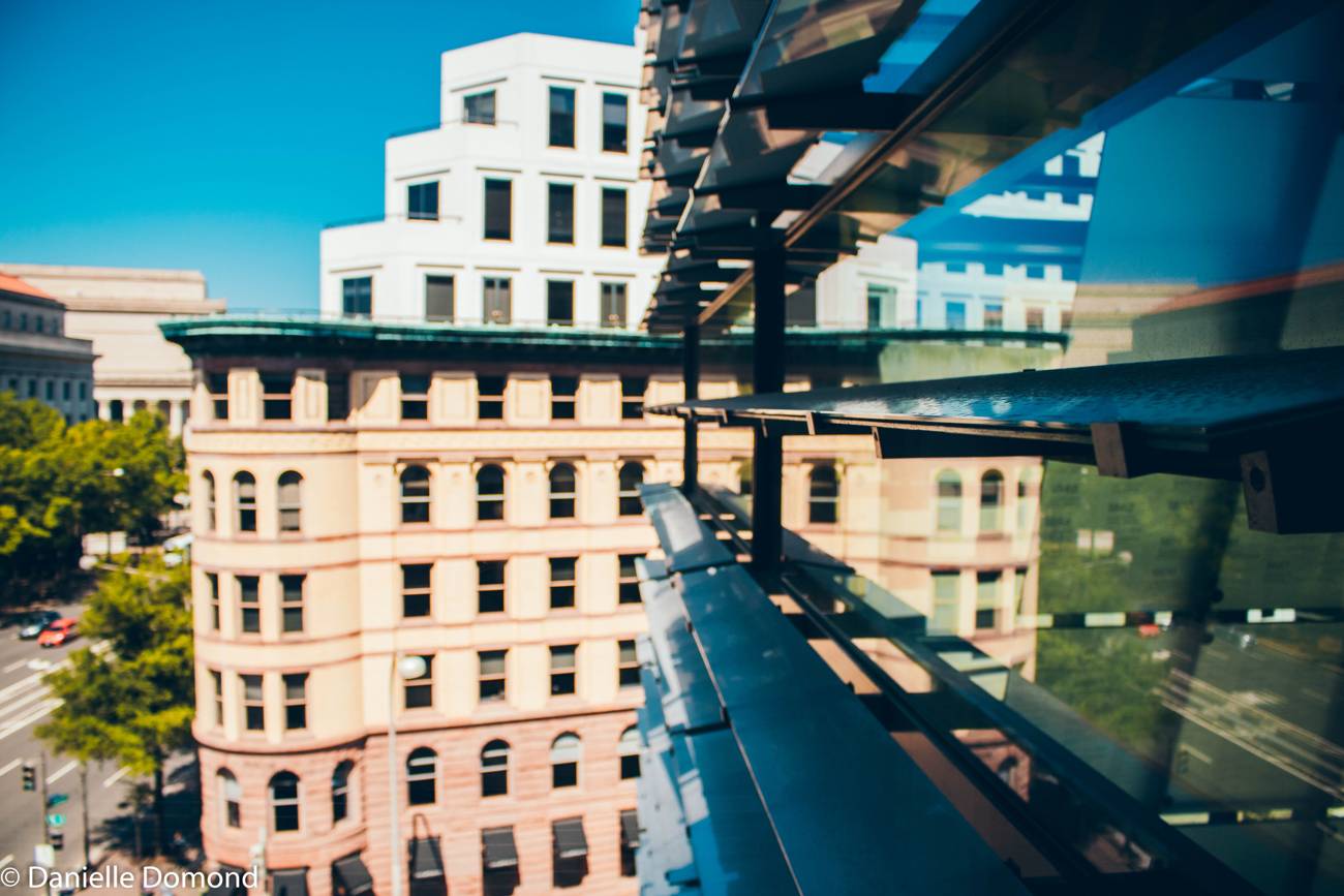 An elevated view down a Washington DC avenue lined with federal buildings and summer trees
