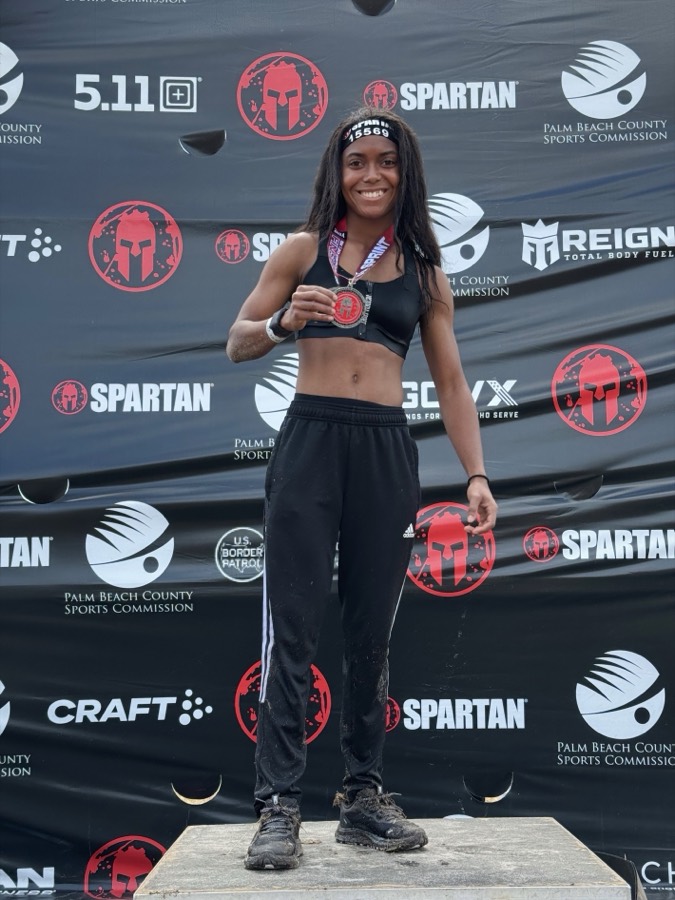 Danielle smiling on the podium with her Spartan race medal