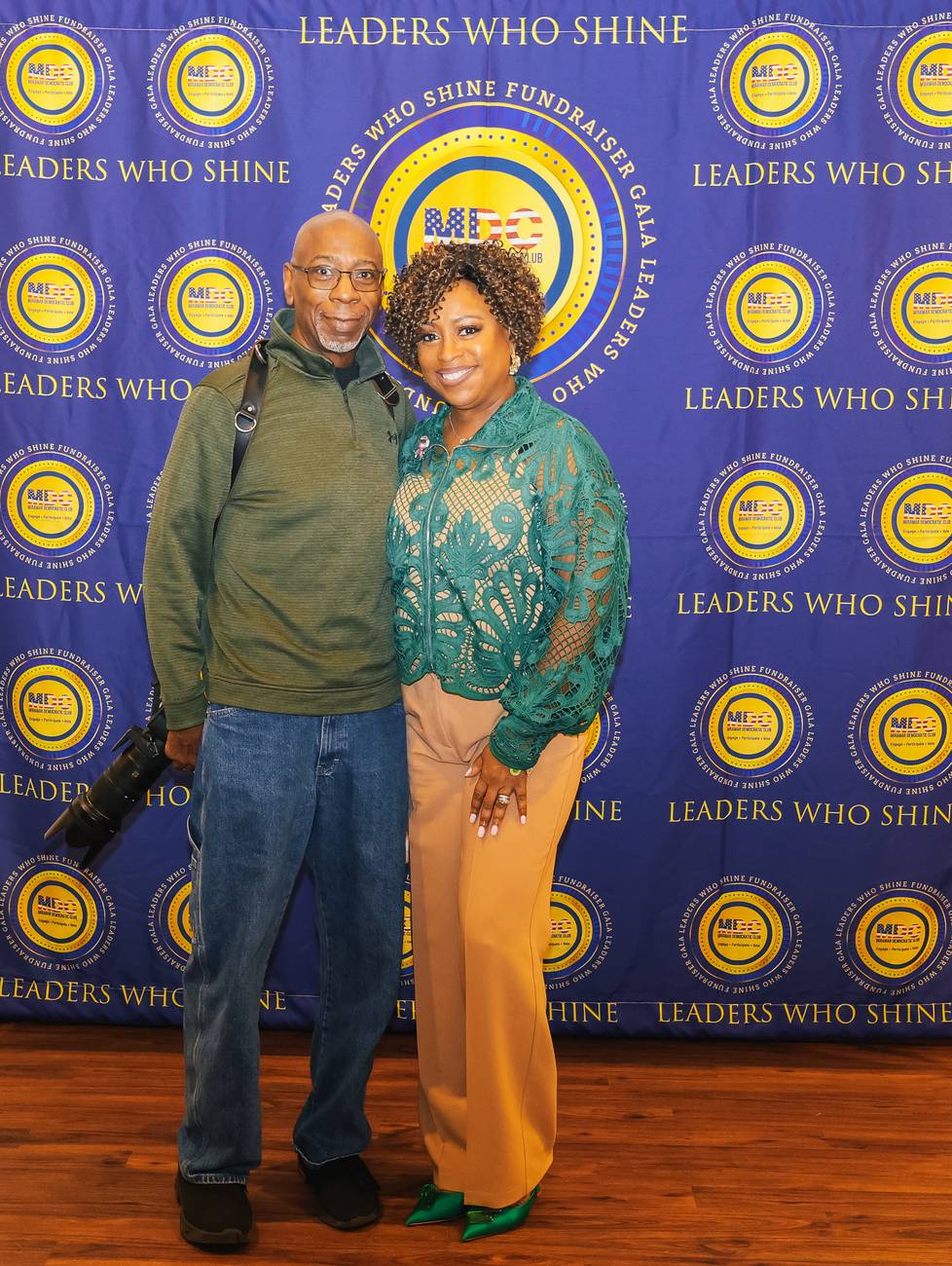 Photojournalist Gregory Reed with his camera and Tammy Reed on the Leaders Who Shine backdrop