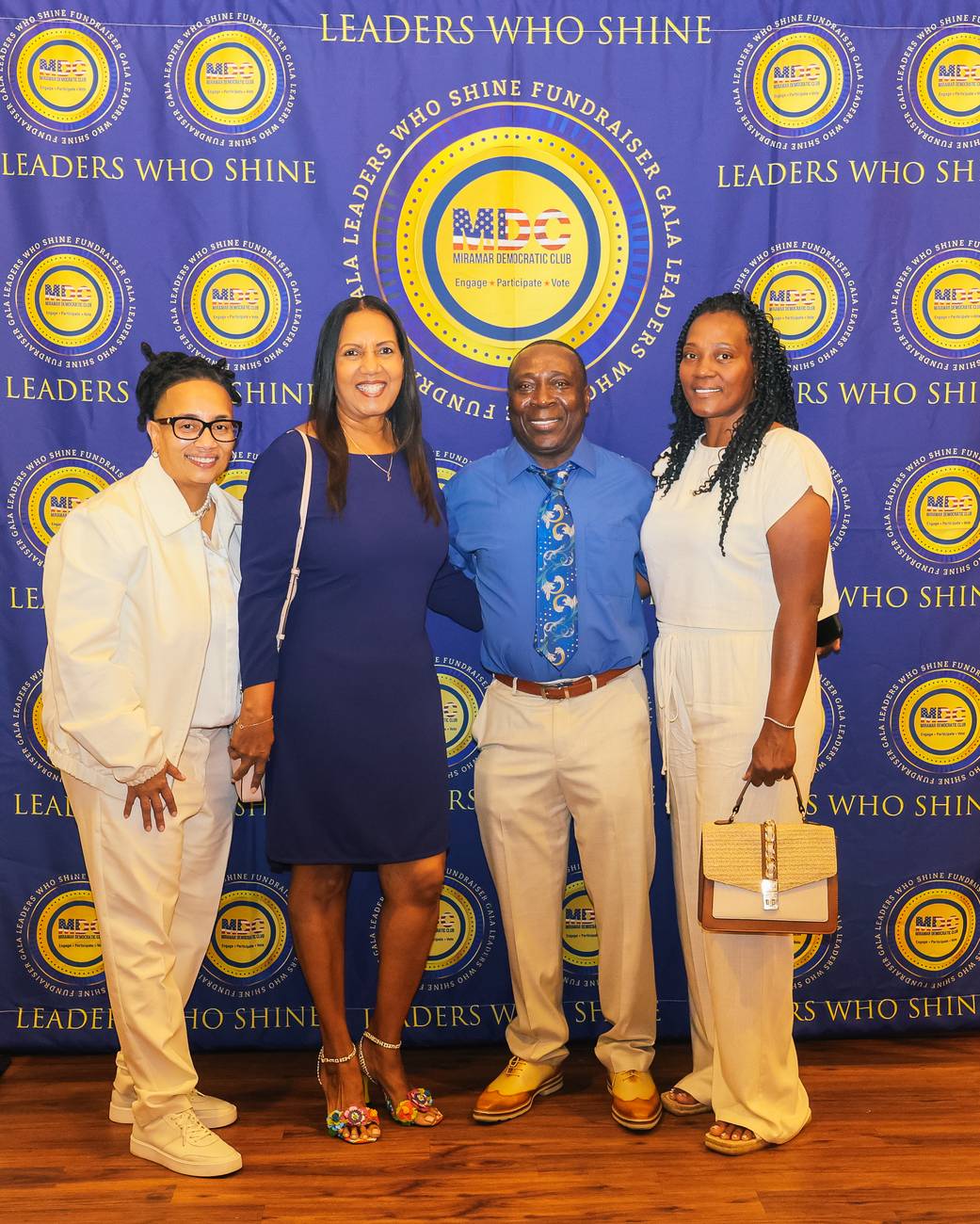 Four guests dressed in blue and cream on the Leaders Who Shine step-and-repeat