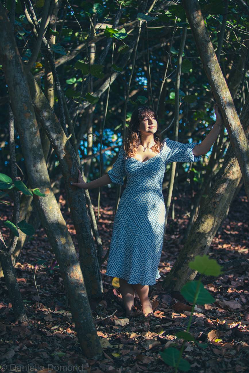 Annalise standing in dappled light among the trees