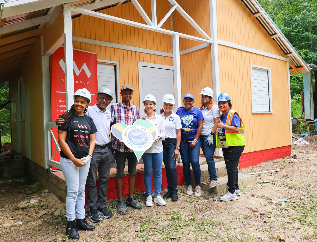 A volunteer in a hard hat painting a new home during the Diaspora Day of Service in Jamaica