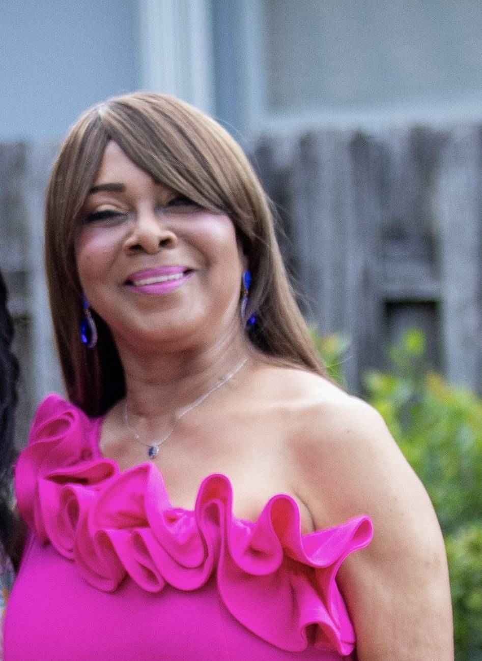 A radiant woman in a fuchsia ruffled dress smiling at her birthday photoshoot