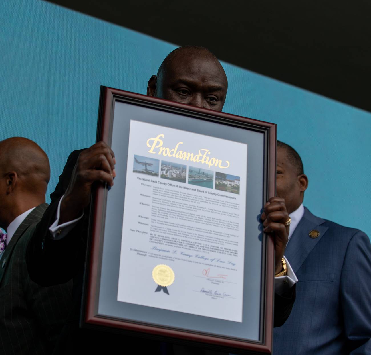 Attorney Ben Crump holding up a framed Miami-Dade County proclamation at the St. Thomas University ceremony