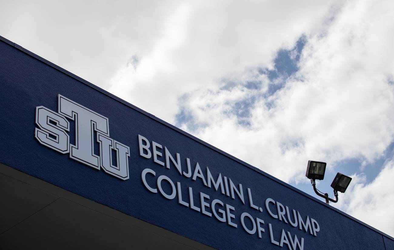 The new Benjamin L. Crump College of Law signage on the St. Thomas University building against a cloudy sky